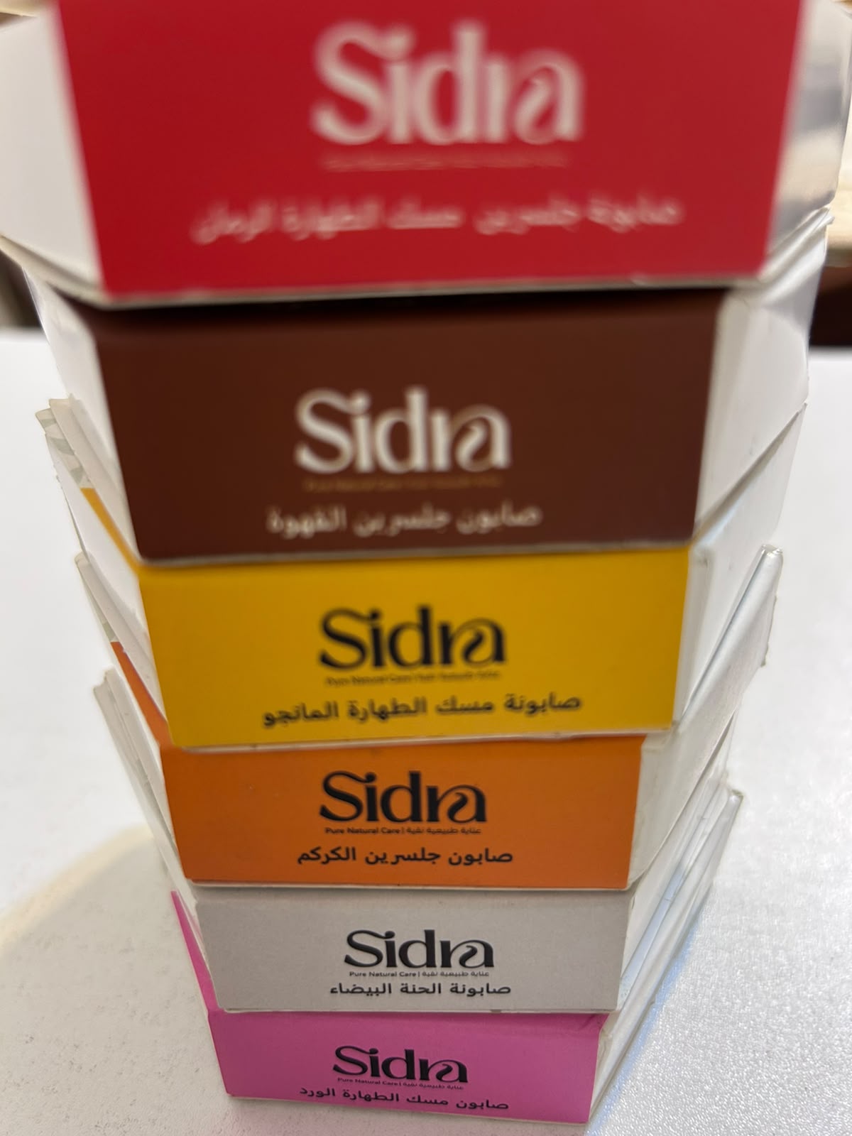 أطراف علب سِدرا مرصوصة فوق بعضها، ويظهر شريط اللون المميّز لكل رائحة على حافة كل علبة.
